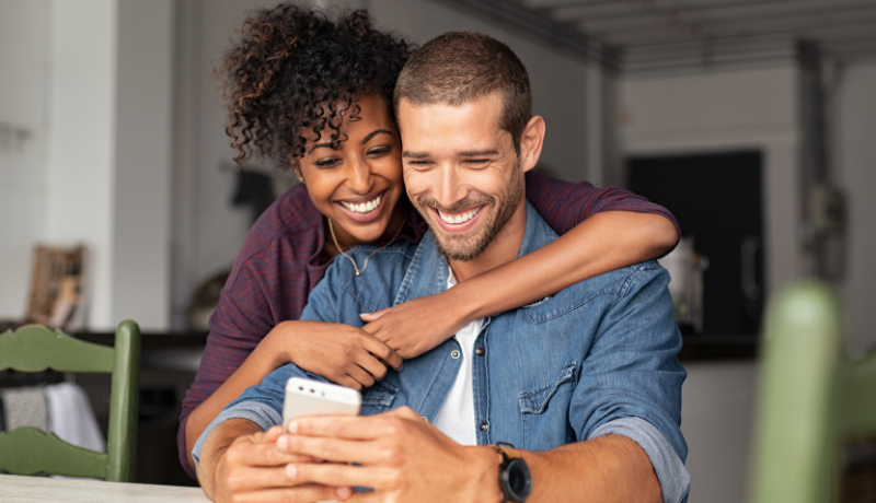 happy couple looking at their phone for loan repayments